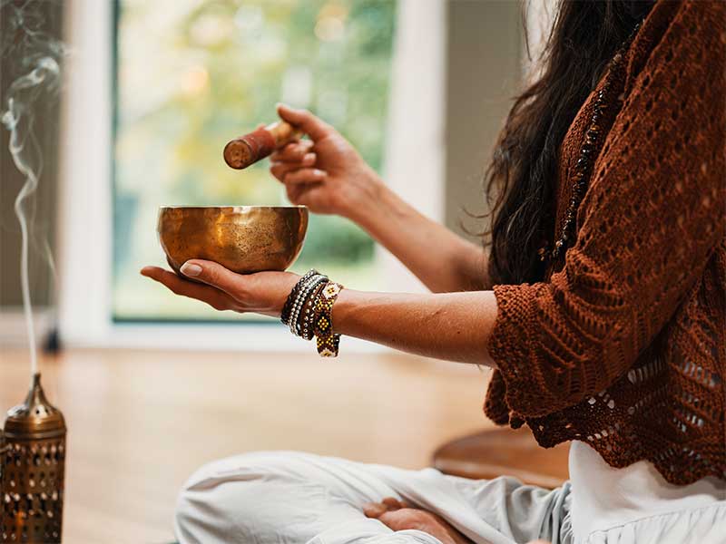Woman preparing to meditate with incense and a meditation bowl